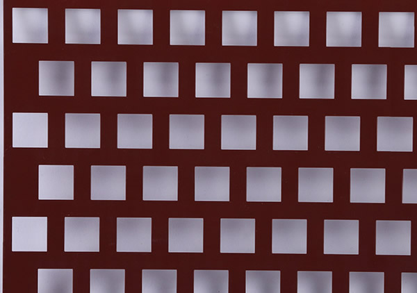 a piece of an aluminum perforated plate with square staggered holes and red powder coating