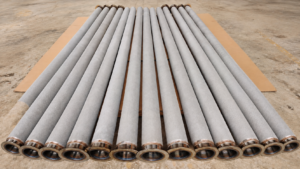 Long sintered metal fiber felt filter cartridges arranged on cardboard in the workshop