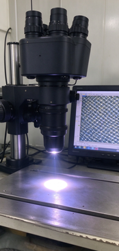 Microscope with a screen displaying magnified metal mesh surface