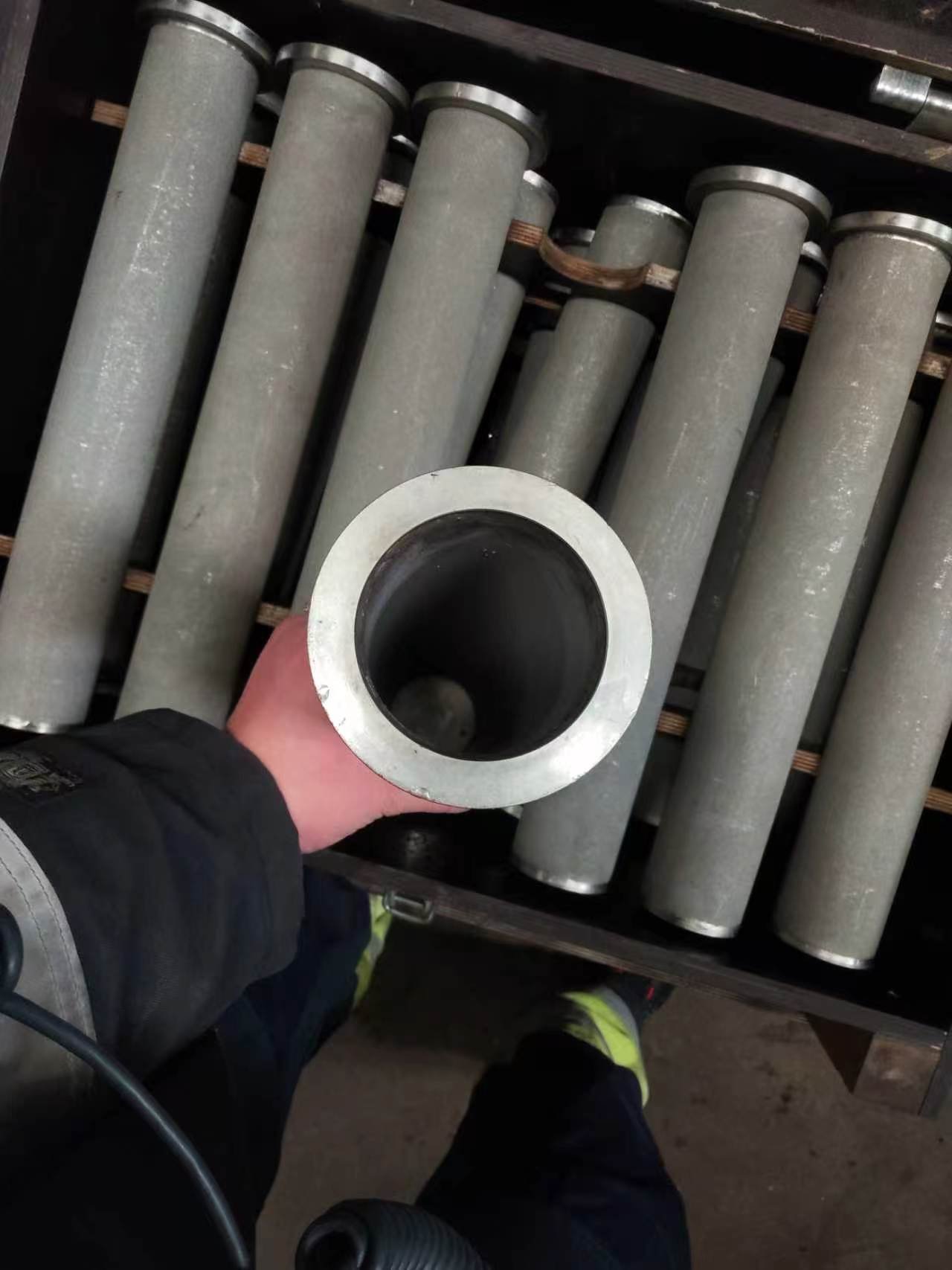 Hand holding the open end of a used porous metal filter cartridge