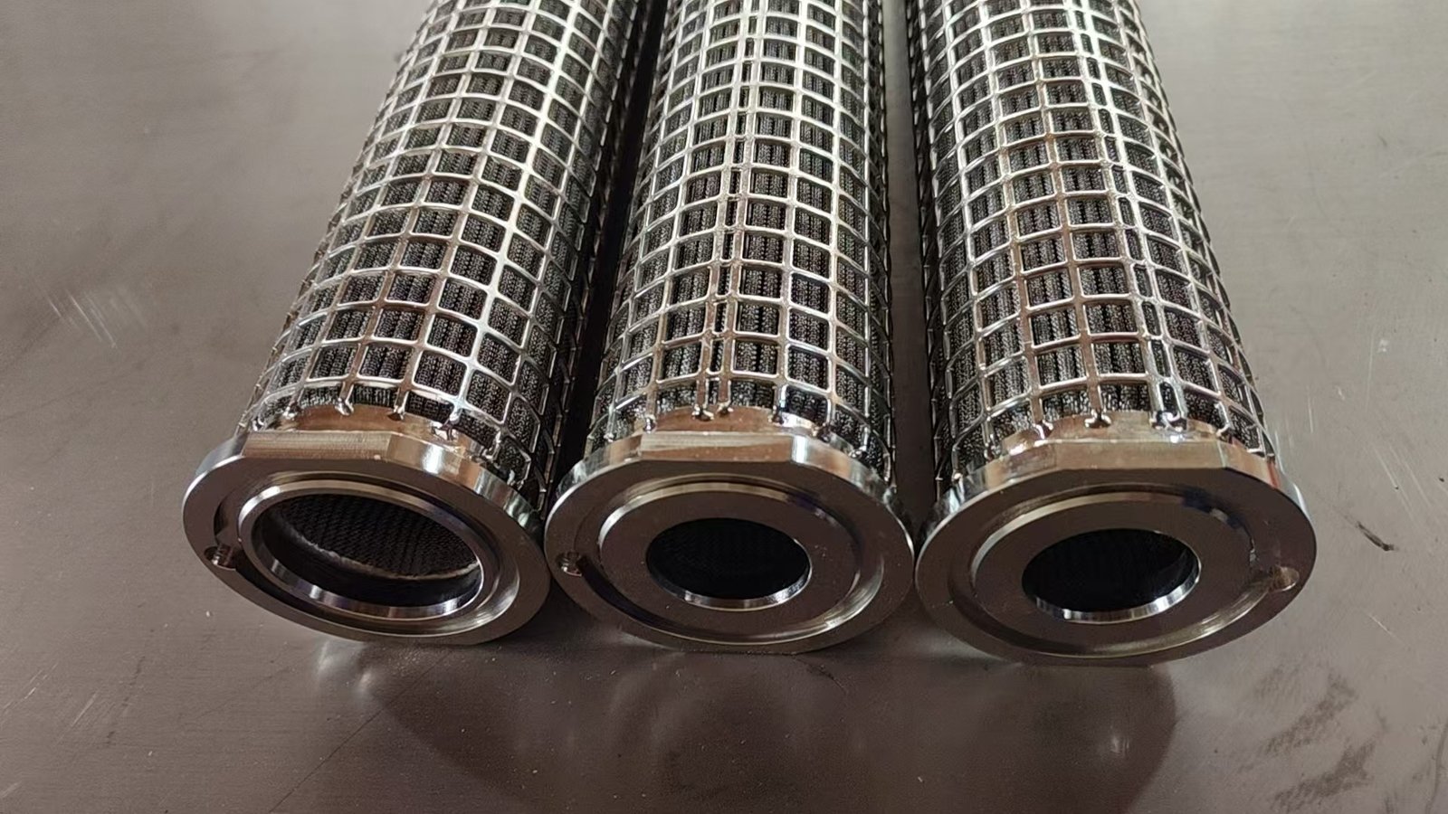 Metal filter cartridges with open-grid external supports and machined end fittings