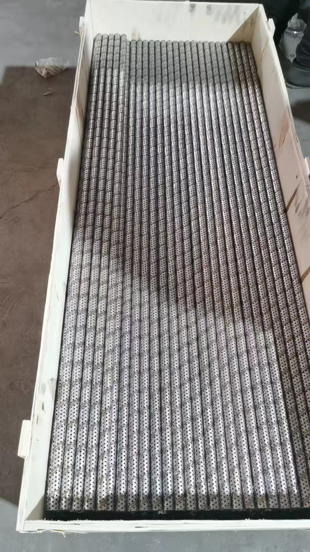 Custom perforated metal tubes ready for shipment Custom perforated metal tubes arranged in a shipping crate