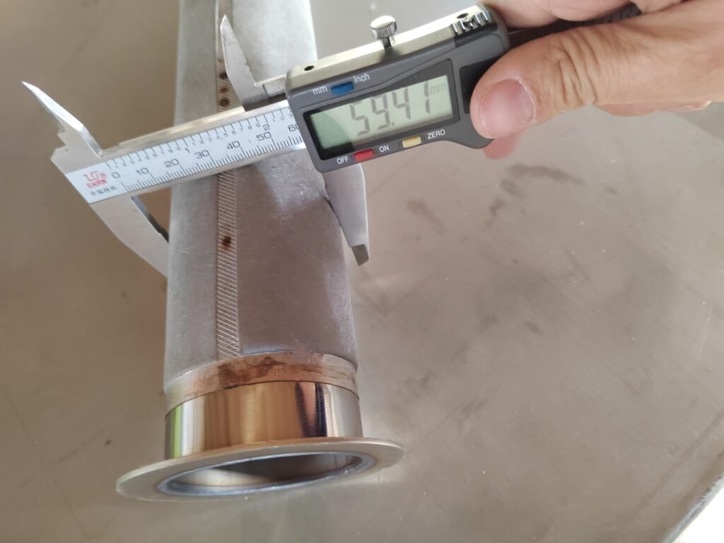 Digital caliper measuring a cylindrical metal fiber felt filter element beside its welded end fitting