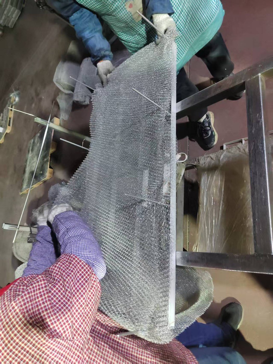 Workers assembling a wire mesh demister pad and its support structure
