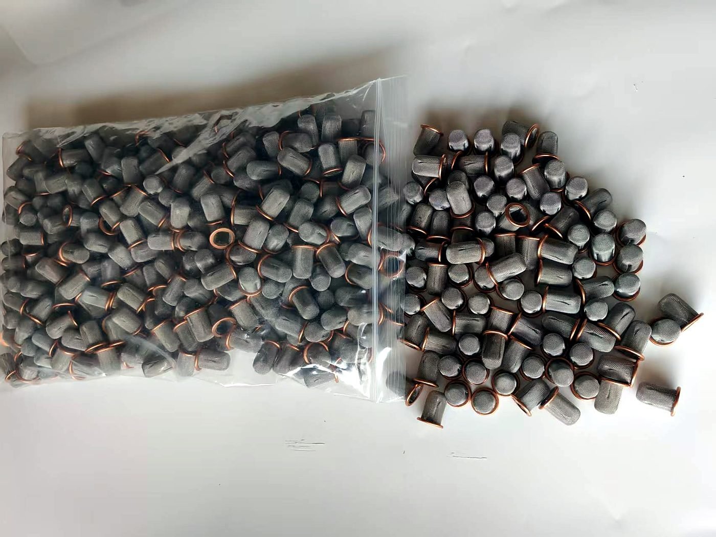 Batch of small cup-shaped wire mesh filter caps with metal rims