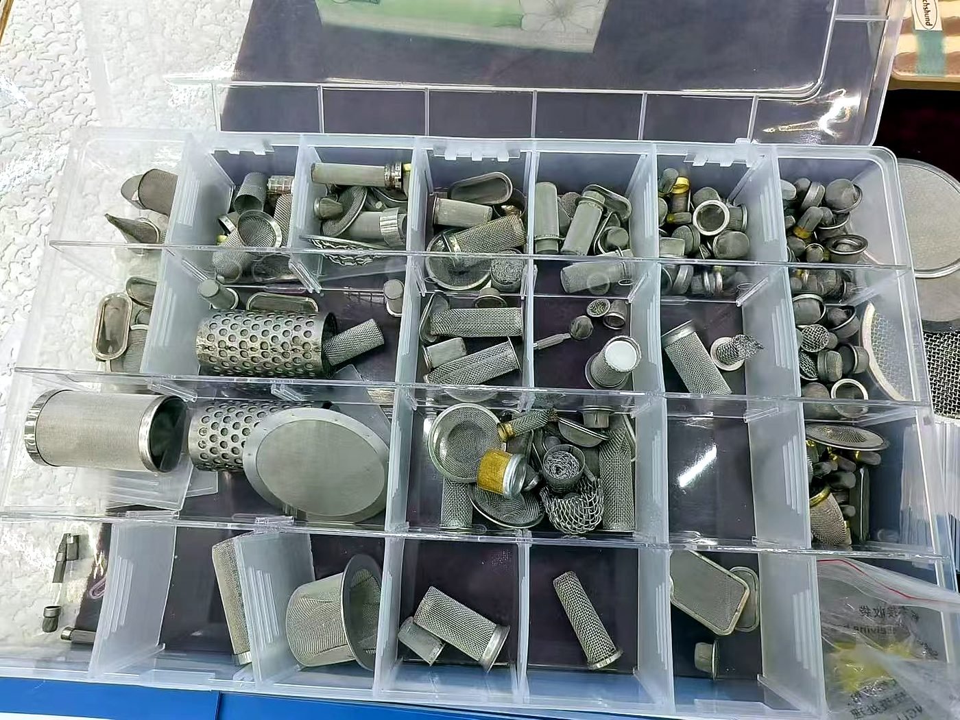 Wire mesh filter caps and other metal filter samples in a compartmented box